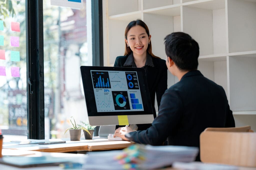 Asian businesspeople discussing graphs and charts showing company performance